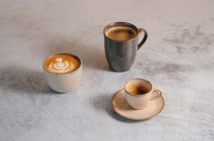 Various coffee drinks, including espresso, latte art, and a mug on a stylish table.